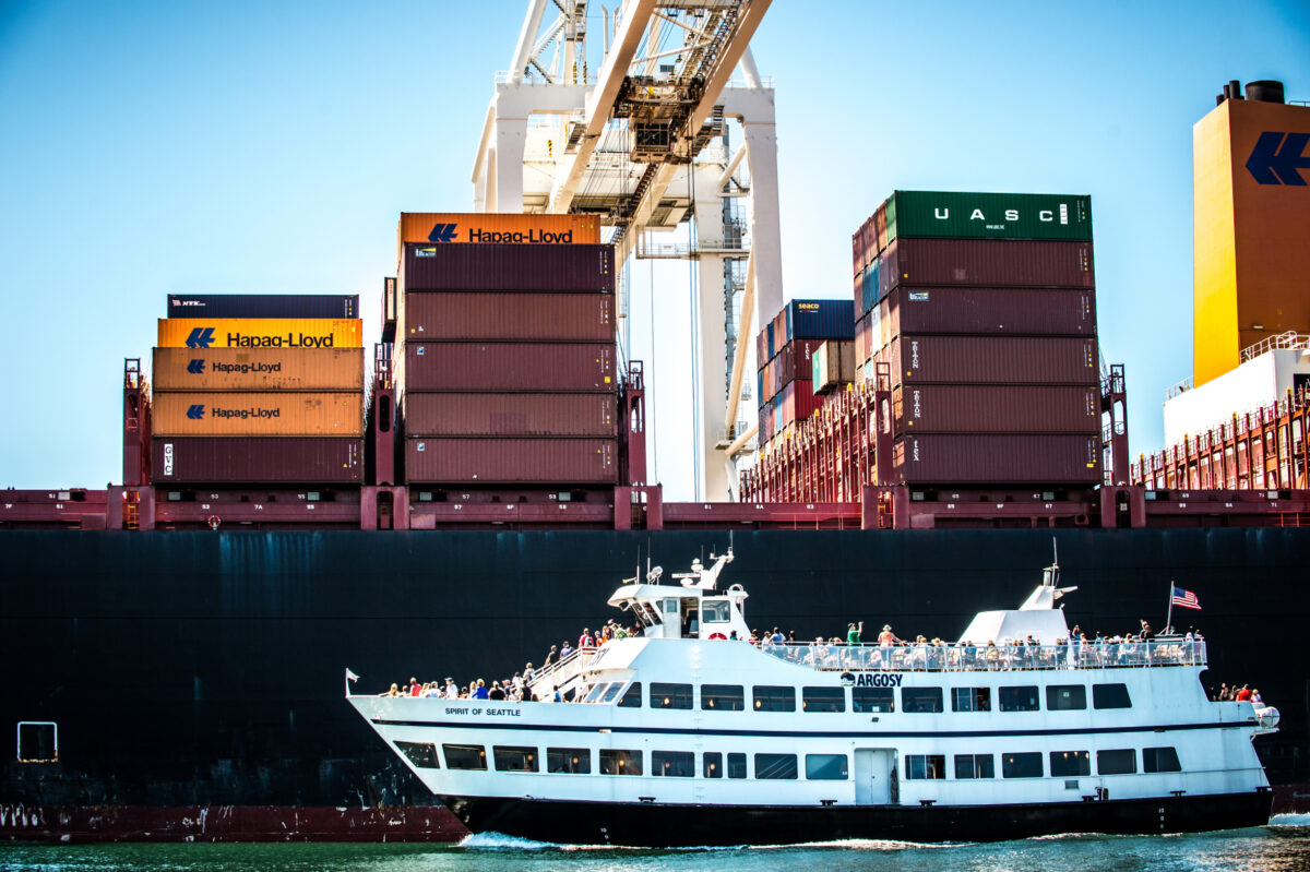 The Argosy Cruises Spirit of Seattle boat in front of port container ships.