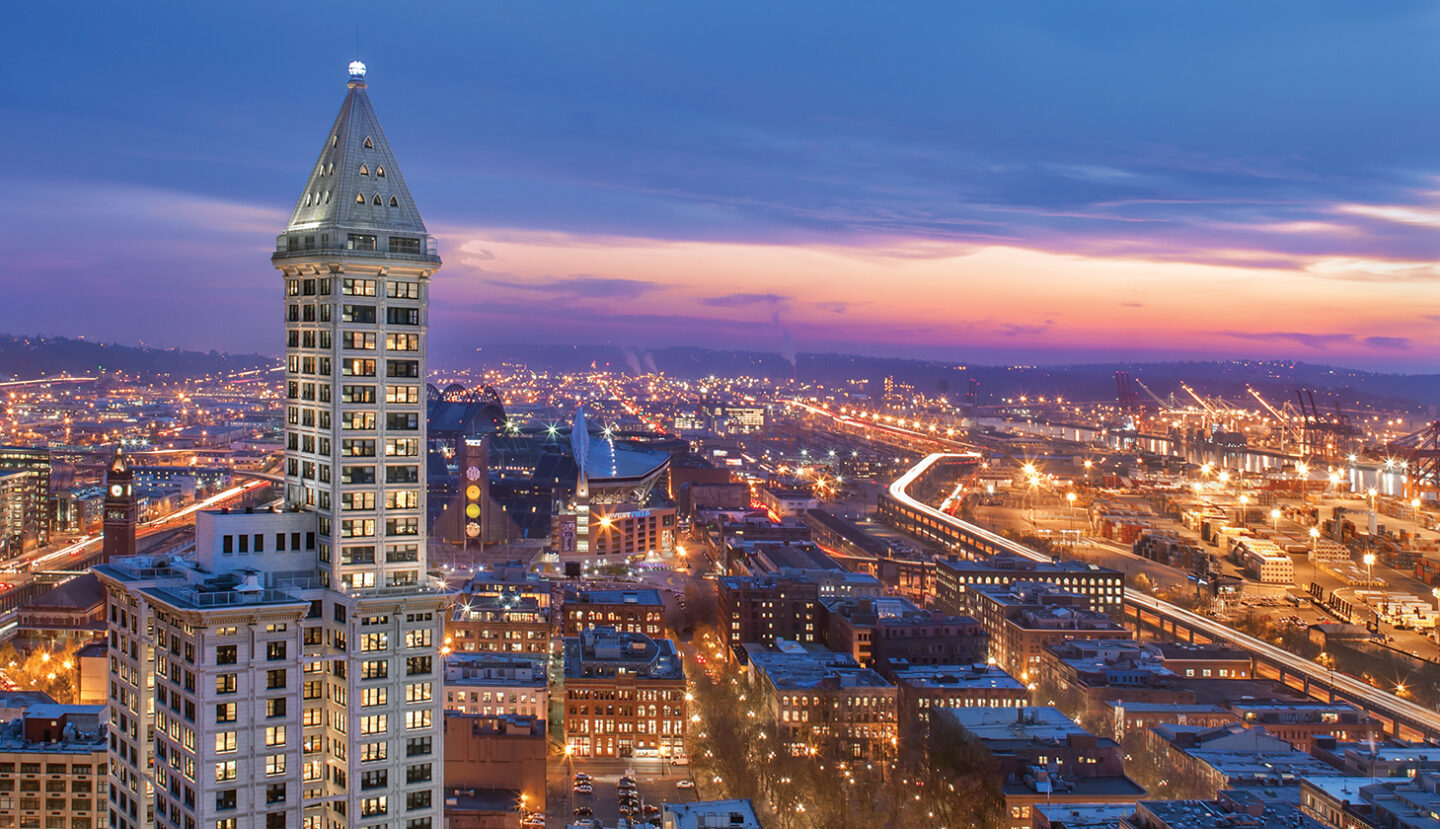 Smith Tower and the Seattle skyline at dusk with city lights.