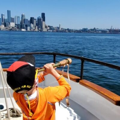 Child having fun with telescope on ship Seattle skyline.
