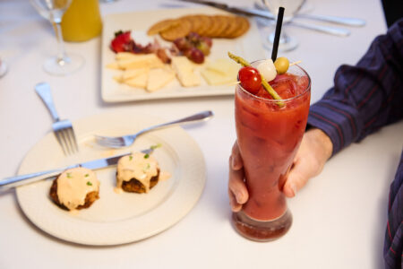 Brunch table with Bloody Mary cocktail and plates of food.