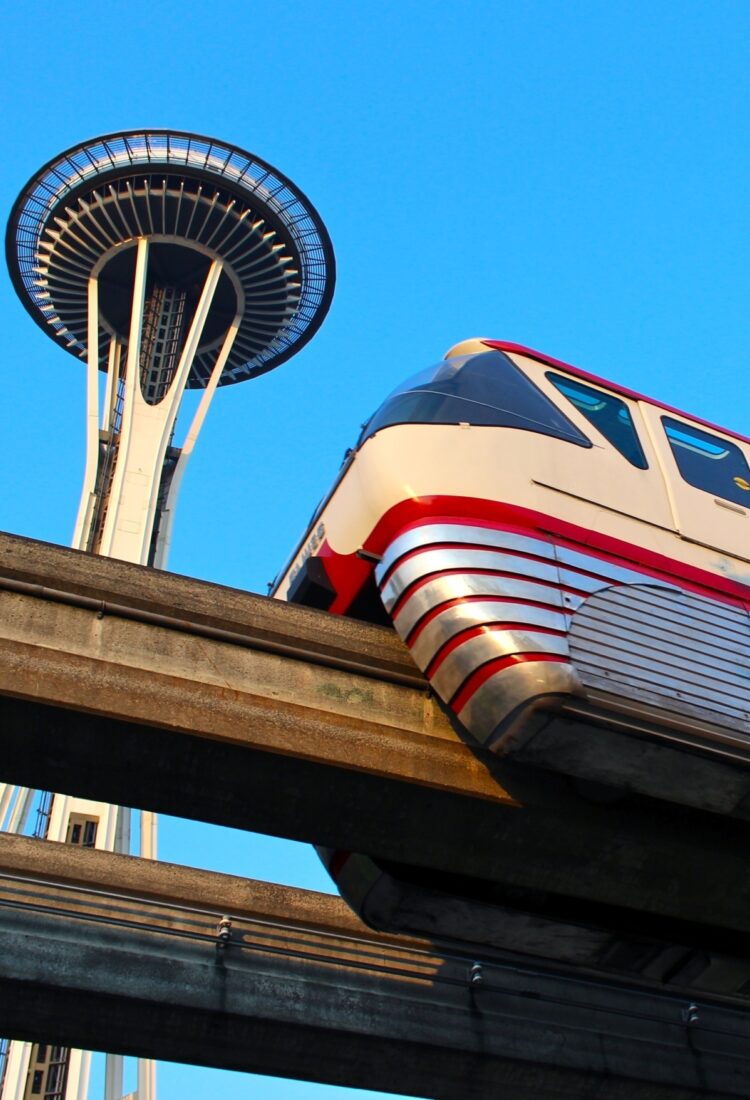 Seattle Monorail Red Train with the Space Needle above and MoPOP to the right.